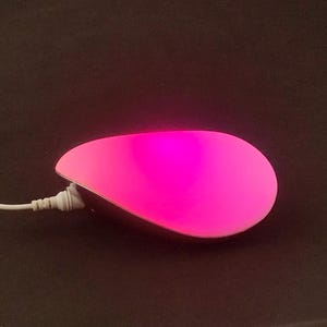 May include: A white and pink teardrop-shaped lamp with a cord.