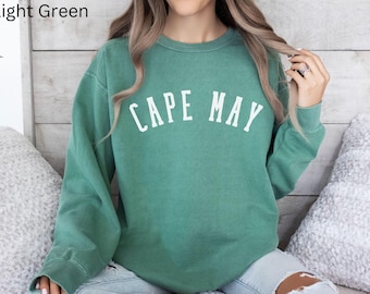 May include: A light green sweatshirt with the text "CAPE MAY" printed in white on the front.