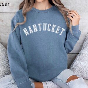 May include: A blue sweatshirt with the word "NANTUCKET" printed in white on the front.