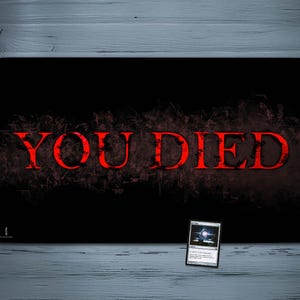 May include: A black rectangular gaming mouse pad with the words "YOU DIED" in red, stylized text. The text is set against a dark, textured background. A Magic: The Gathering card is in the lower right corner.