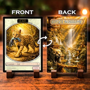 May include: A double-sided game card featuring a front side with a spotted cat holding a blue lizard in its mouth, labeled 'CAT' and 'Creature - Cat'. The back side displays a golden landscape with waterfalls, temples, and a stone cat head.
