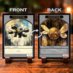 May include: Two rectangular trading cards labeled THOPTER, displayed front and back on wooden stands. The front card shows a mechanical flying machine against a cloudy sky. The back card features a golden, insect-like mechanical creature with iridescent wings.