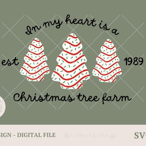 Puede incluir: Diseño digital con tres árboles de Navidad decorados con rayas rojas y chispas verdes. El texto dice "In my heart is a Christmas tree farm", con "est 1989" y un logotipo.