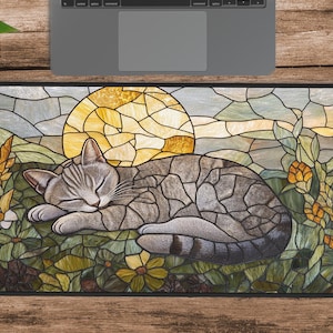 Puede incluir: Una ilustración de estilo vitral de un gato gris durmiendo en una cama de flores y hojas. El gato está enroscado con los ojos cerrados. El fondo presenta un gran sol amarillo y un cielo azul.