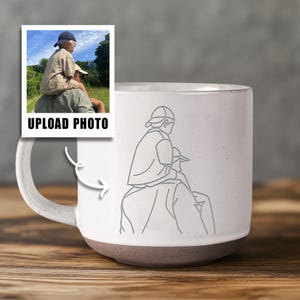 May include: White ceramic mug with a grey base and handle. The mug has a line drawing of a person carrying another person on their shoulders. A small photo with the text "UPLOAD PHOTO" is on the left side of the mug.