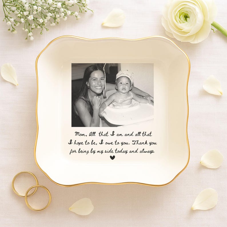 K&ouml;nnte beinhalten: Eine wei&szlig;e Keramikschale mit goldenem Rand, mit einem Schwarz-Wei&szlig;-Foto von Mutter und Kind. Die Schale hat eine handschriftliche Nachricht: "Mama, alles, was ich bin und alles, was ich sein m&ouml;chte, verdanke ich dir."