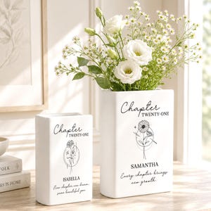 May include: Two white rectangular ceramic vases featuring black printed text and floral line art. The smaller vase reads Chapter TWENTY-ONE ISABELLA New chapter, new dream, same beautiful you. The larger vase reads Chapter TWENTY-ONE SAMANTHA Every chapter brings new growth.