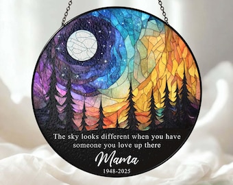 May include: Round stained glass window art with a night sky and mountain scene. The design features a full moon, stars, and trees. Text reads "The sky looks different when you have someone you love up there" and "Mama 1948-2025".