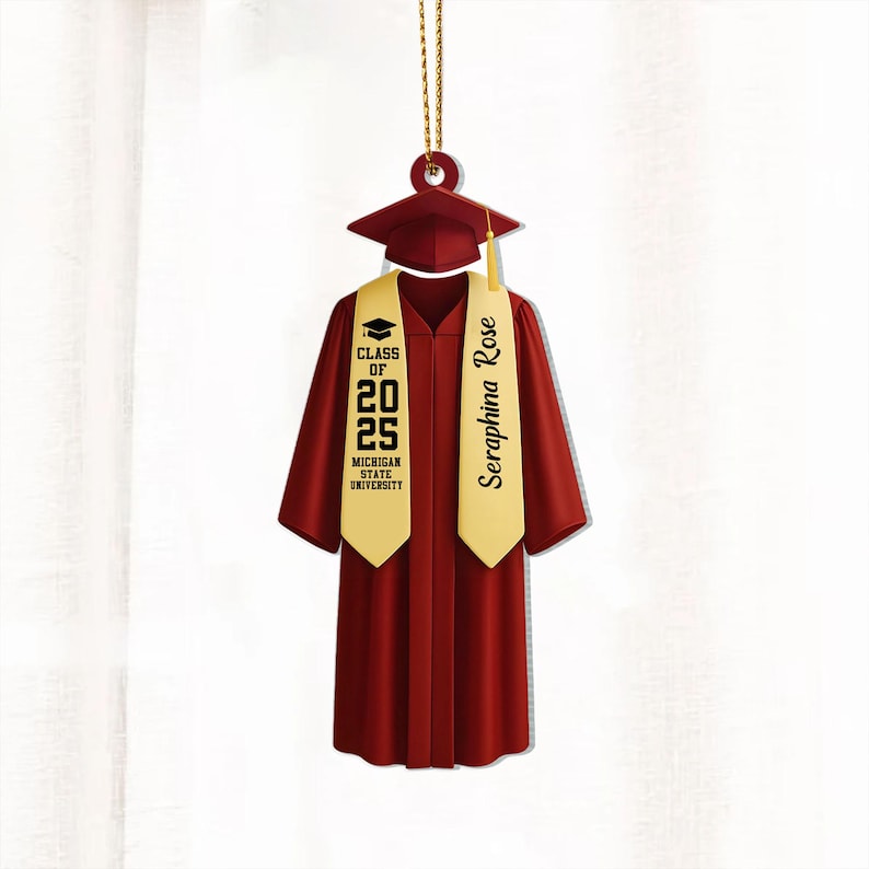 May include: A red graduation cap and gown ornament with a gold tassel and a gold sash that says "Seraphina Rose" and "Class of 2025 Michigan State University".
