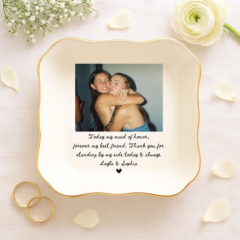 May include: A white ceramic dish with a gold rim, featuring a photograph of two people embracing. The dish has text that reads "Today my maid of honor, forever my best friend. Thank you for standing by my side today & always Layla & Sophia."