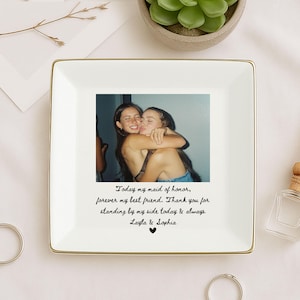 May include: A square white ceramic trinket dish with a gold rim. The dish features a photograph of two women embracing. Below the photo is handwritten text that reads "Today my maid of honor, forever my best friend..."
