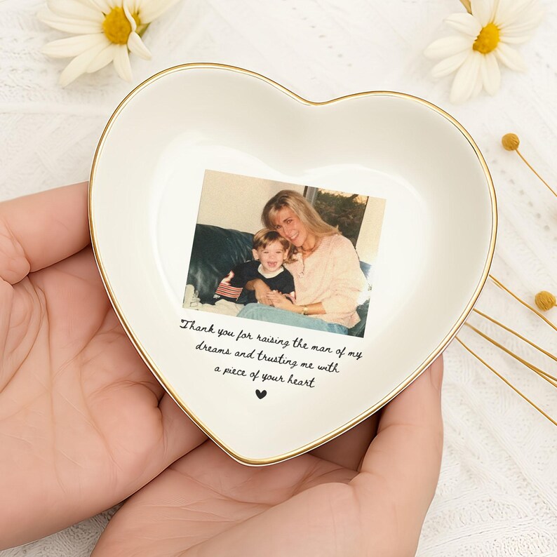 K&ouml;nnte beinhalten: Herzf&ouml;rmige Keramik-Schmuckschale mit goldenem Rand, mit einem gedruckten Foto von Mutter und Kind. Die Schale hat eine cremefarbene Oberfl&auml;che und den Text "Thank you for raising the man of my dreams and trusting me with a piece of your heart."