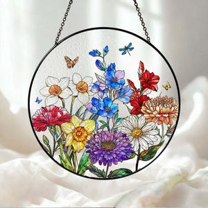 May include: A round stained glass panel featuring a colorful floral design. The artwork includes various flowers in shades of red, yellow, blue, and purple, with butterflies and dragonflies. The panel is framed in black and hangs from a chain.