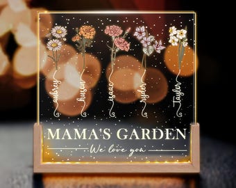 May include: A light-up sign with a white background and gold lettering. The sign says "Mama's Garden - We love you" and features five stylised flowers with names written underneath each flower: Aubrey, Hudson, Isaac, Ryder, and Taylor.