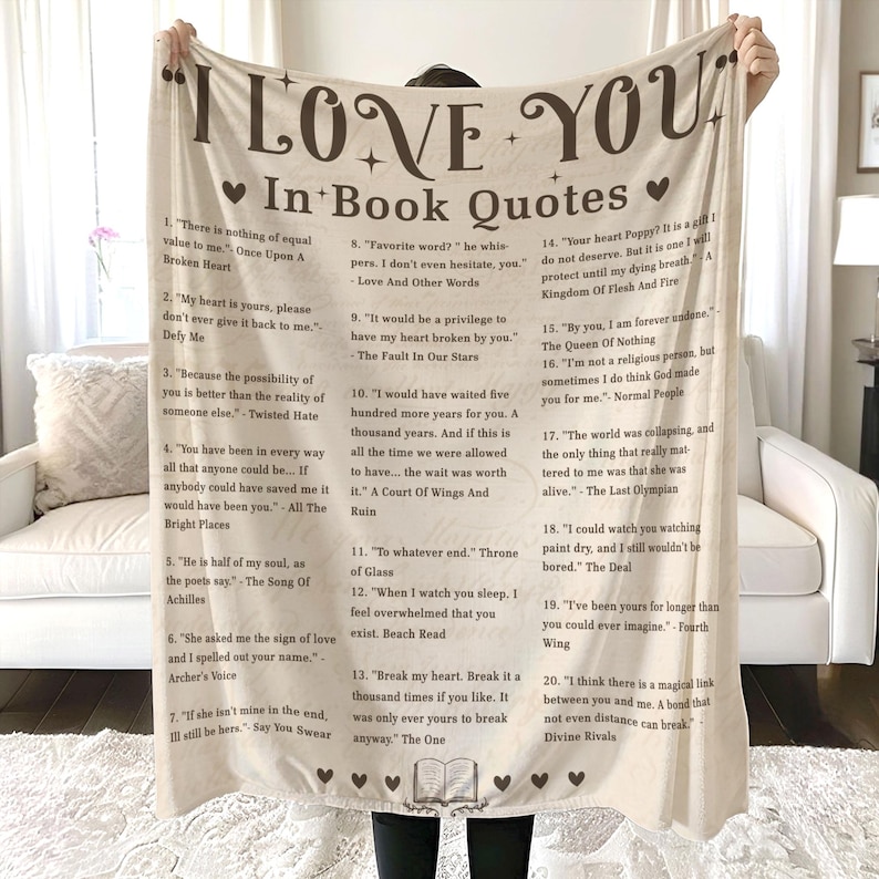 May include: A beige throw blanket with brown text featuring quotes from popular books. The text includes quotes from "The Fault in Our Stars", "The Song of Achilles", "Twisted Hate", "All the Bright Places", "A Court of Wings and Ruin", "Throne of Glass", "Beach Read", "The One", "The Queen of Nothing", "Normal People", "The Last Olympian", "The Deal", "Fourth Wing", and "Divine Rivals".
