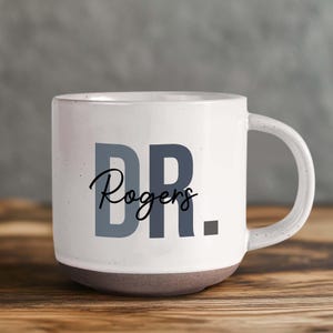 May include: White ceramic mug with a gray and black design that says "DR. Rogers".