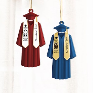 May include: Two graduation cap ornaments with the text "Class of 2025" and "Michigan State University". The ornaments are red and blue with gold tassels and white and gold sashes with the name "Seraphina Rose" printed on them.