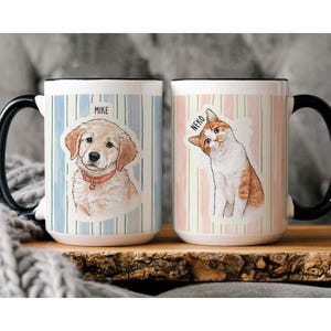 K&ouml;nnte beinhalten: Zwei Keramikbecher mit schwarzen Griffen. Ein Becher zeigt eine Illustration eines Golden Retrievers mit dem Namen "MIKE" dar&uuml;ber, vor einem blau-wei&szlig; gestreiften Hintergrund. Der andere Becher hat eine Katzenillustration mit dem Namen "NEKO" und einem rosa-wei&szlig; gestreiften Hintergrund.