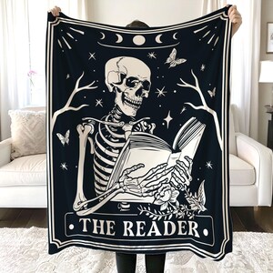 Puede incluir: Tapiz en blanco y negro con un esqueleto leyendo un libro. El tapiz tiene un tema celestial con estrellas, lunas y una mariposa. El texto "THE READER" est&aacute; impreso en la parte inferior.