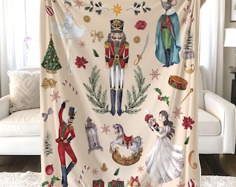 May include: A cream-colored fleece blanket with a Nutcracker theme. The blanket features a Nutcracker soldier, a ballerina, a mouse king, a rocking horse, and other festive details.
