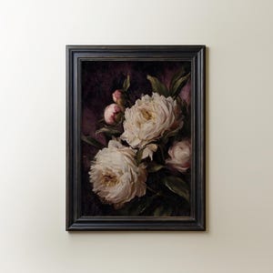 May include: A framed floral painting featuring white peonies with yellow centers and pink buds against a dark purple background. The painting is in a black wooden frame, creating a classic and elegant aesthetic.