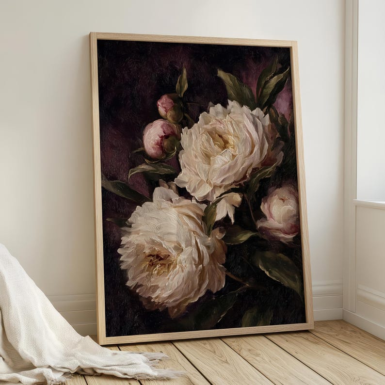 May include: A framed floral print featuring large, creamy white peonies with hints of pink against a dark, moody background. The painting style is reminiscent of classic oil paintings, with visible brushstrokes and a soft, romantic feel. The frame is a light wood.