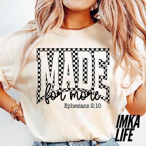 May include: Cream-colored t-shirt with the text "MADE for more" in a black and white checkered design. The text "Ephesians 2:10" is below the main text. The brand name "IMKA LIFE" is in the bottom right corner.