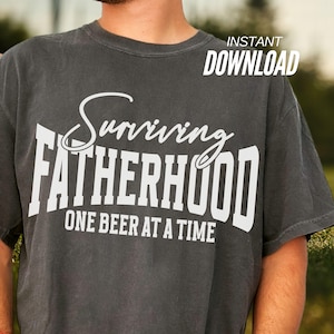 Puede incluir: Una camiseta gris oscura con texto blanco que dice "Surviving Fatherhood One Beer at a Time".