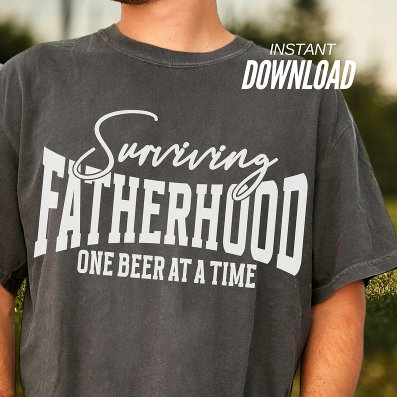 Puede incluir: Una camiseta gris oscura con texto blanco que dice "Surviving Fatherhood One Beer at a Time".