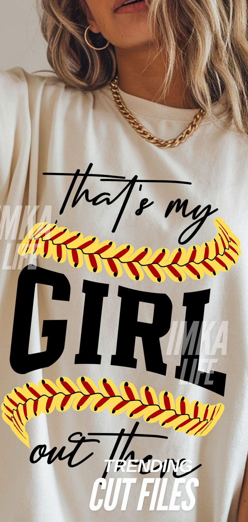 Peut inclure: T-shirt cr&egrave;me avec l'inscription noire "that's my GIRL", orn&eacute;e de coutures de softball jaunes et rouges. Les mots "out the" et "TRENDING CUT FILES" sont &eacute;galement visibles.