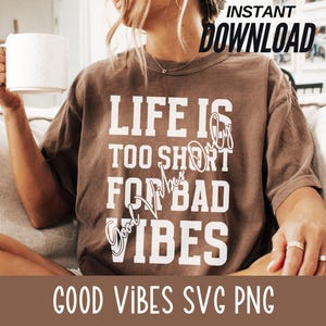 May include: A brown t-shirt with the text "Life is too short for bad vibes" printed in white. The shirt is being worn by a person.