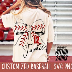 May include: A white t-shirt with a baseball-themed bow design. The bow is made of red and white baseball stitching. The number 12 and the name "Jamie" are written on the bow. The text "READY WITHIN 24HRS" is in the bottom right corner of the image.