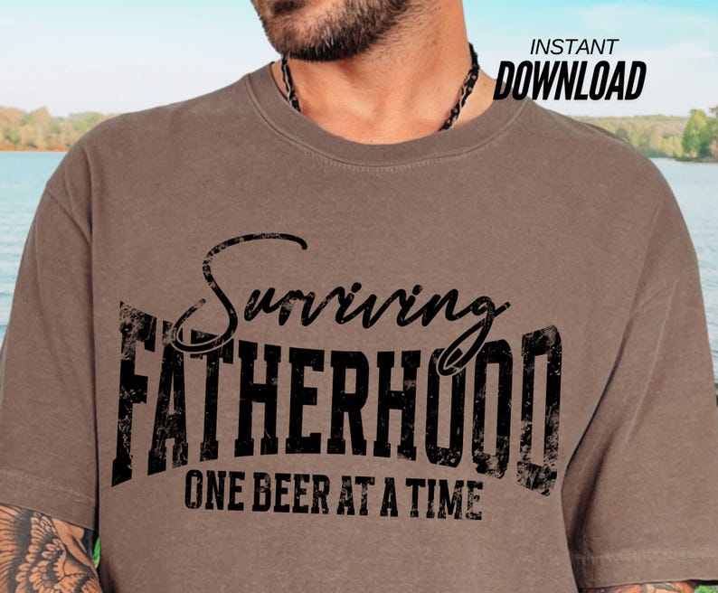 Puede incluir: Una camiseta marr&oacute;n con el texto "Surviving Fatherhood One Beer at a Time" en negro.
