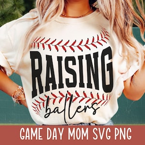 May include: White t-shirt with a red and white baseball graphic and the text "Raising Ballers".