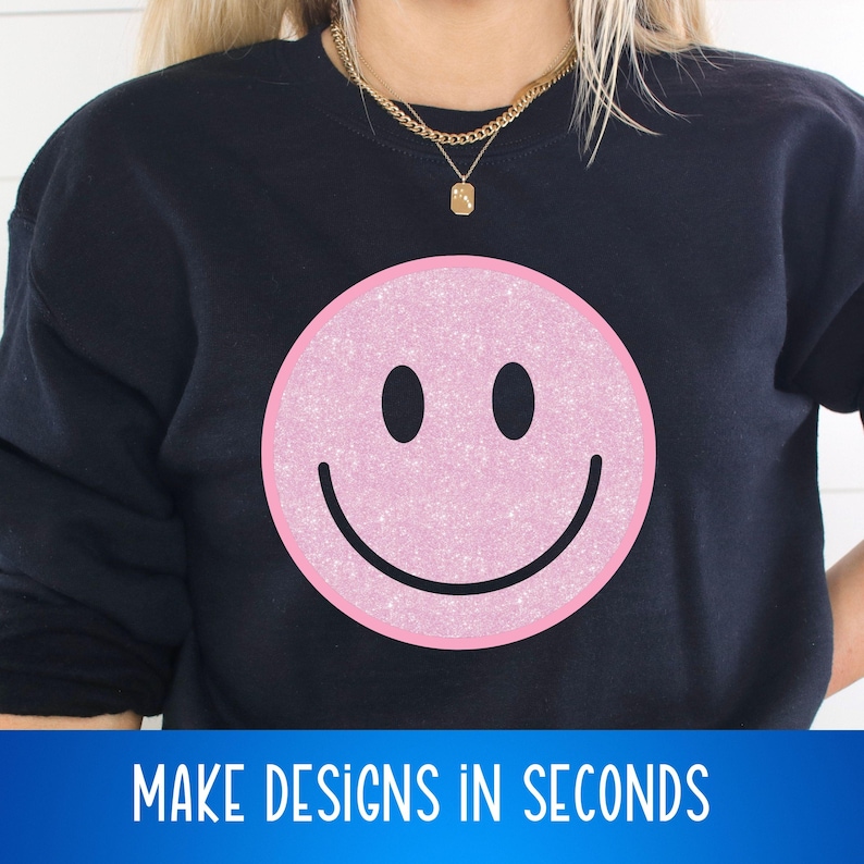 May include: A black sweatshirt with a pink glitter smiley face graphic. The text "MAKE DESIGNS IN SECONDS" is printed below the graphic.