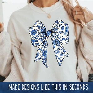 May include: A white sweatshirt with a blue and white floral bow design. The bow is centered on the front of the sweatshirt.