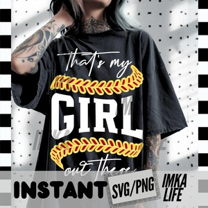 Peut inclure: T-shirt noir avec l'inscription blanche "That's my GIRL out there", orn&eacute;e d'&eacute;l&eacute;ments de baseball jaunes et rouges. Le t-shirt porte &eacute;galement les mots "INSTANT SVG/PNG IMKA LIFE" en bas.