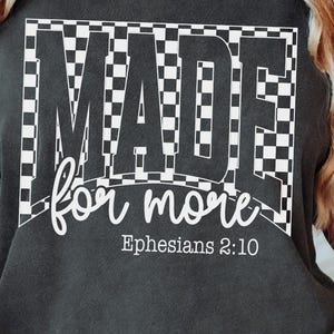 May include: Dark gray t-shirt with the words "MADE for more" in a bold, checkered design. Below, the text "Ephesians 2:10" is printed. The words "UNIQUE CUT FILES" are at the bottom.