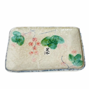Peut inclure: Un plat de service rectangulaire en céramique avec un fond blanc et un bord bleu. Le plat est décoré d'un motif floral de feuilles vertes et de baies roses. Le mot "楽茶" est écrit en noir sur le plat.