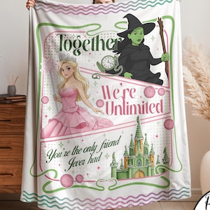 Peut inclure: Une couverture blanche avec un motif rose et vert, avec le texte "Together We're Unlimited". La couverture présente des illustrations d'une princesse, d'une sorcière et d'un château. La couverture est tenue par une personne.