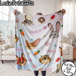 Puede incluir: Una manta azul claro con personajes de dibujos animados, zanahorias, huellas de patas y estrellas. El nombre "EMILY" est&aacute; impreso en rosa. La manta tiene el texto "LeslieFritzGifts" en la esquina superior izquierda y "Pick More Style In Listing" en la inferior derecha.