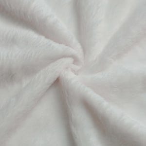 Puede incluir: Primer plano de una tela suave, blanca y esponjosa. El material tiene una textura afelpada con fibras visibles y un ligero brillo. La tela est&aacute; dispuesta en pliegues suaves, creando una sensaci&oacute;n de profundidad y suavidad. Ideal para mantas, mantas o ropa.