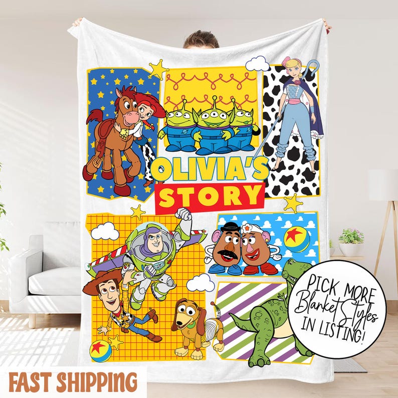 Puede incluir: Manta blanca con personajes de dibujos animados de Toy Story. La manta presenta a Woody, Buzz Lightyear y otros personajes, con el texto "Olivia's Story". La manta tambi&eacute;n tiene el texto "Fast Shipping".