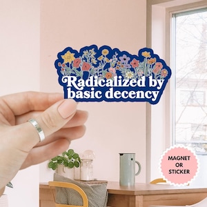 May include: A blue sticker with a floral design and the text "Radicalized by basic decency". The sticker is available as a magnet or sticker.