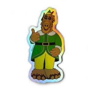 May include: A holographic sticker featuring a green and yellow elf character with a brown furry face and large ears. The character is giving a thumbs up and has a red and white hat with a feather. The sticker has the text "@BEENOTLARE" on the side.