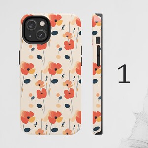 May include: A phone case with a floral pattern. The case is white with red, orange, and yellow flowers. The case has a cutout for the camera lens.