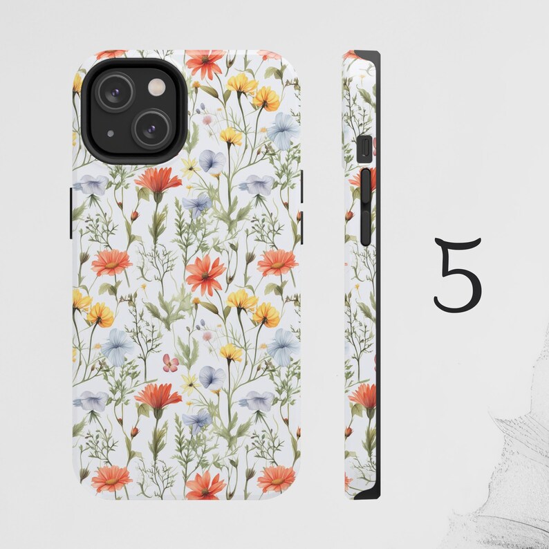 May include: A white phone case with a floral pattern featuring orange, yellow, and blue flowers. The case has a black camera cutout and a black border.