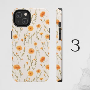 May include: A white phone case with a pattern of yellow flowers. The case has a black camera cutout and a black side.