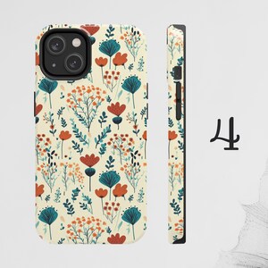 May include: A phone case with a floral pattern featuring red, orange, and blue flowers on a cream background. The case has a cutout for the camera lens.