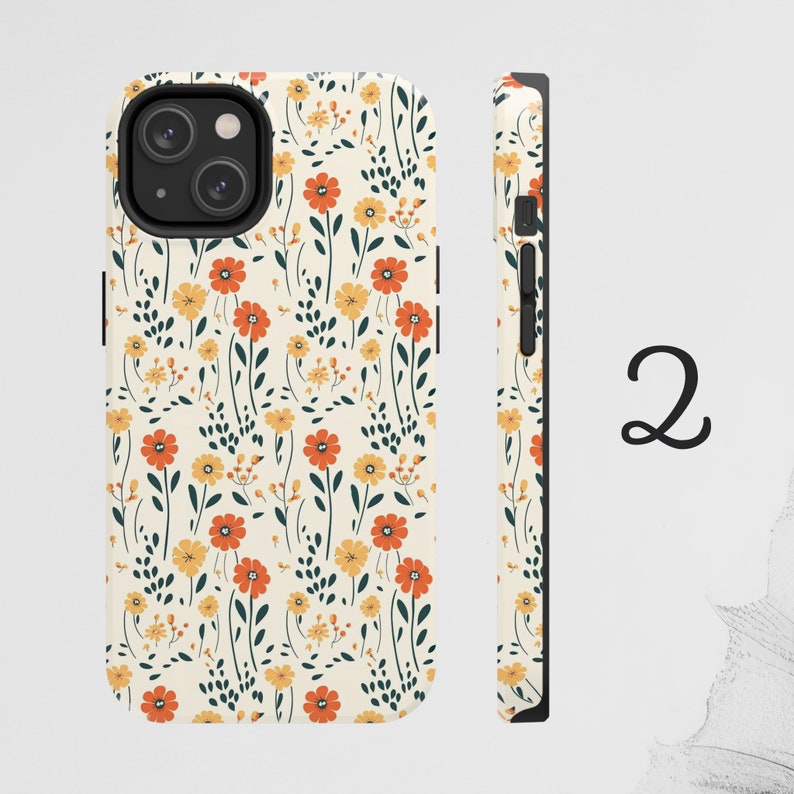 May include: A white phone case with a floral pattern featuring orange, yellow, and green flowers. The case has a black camera cutout and a black side.
